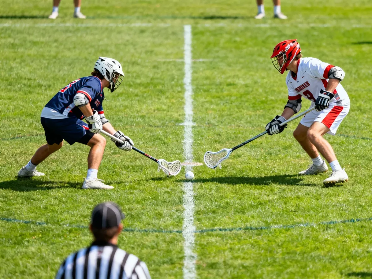 Zawodnicy lacrosse podczas wznowienia na trawiastym boisku